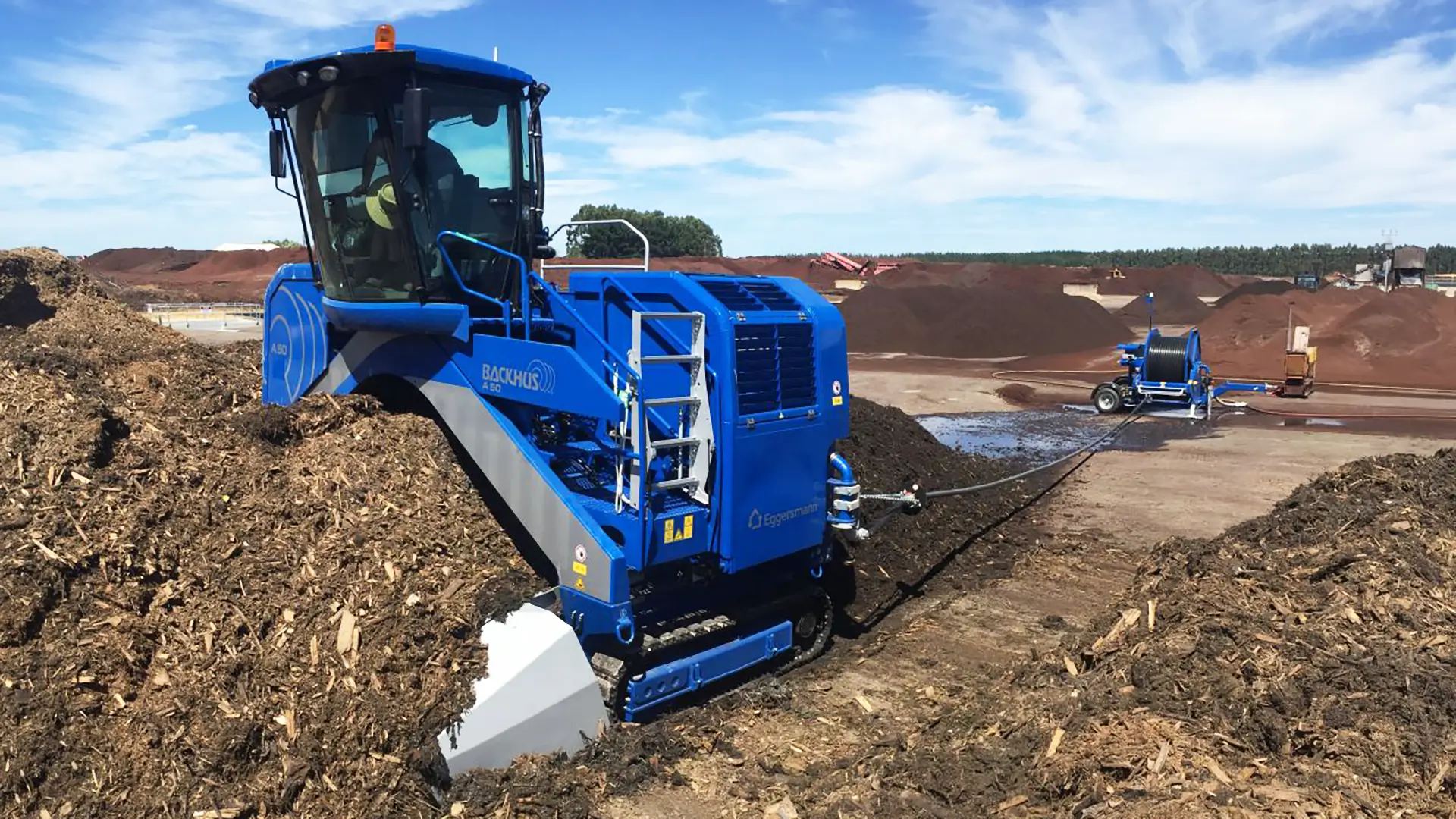 A BACKHUS self-propelled compost turner turns a long windrow of compost.