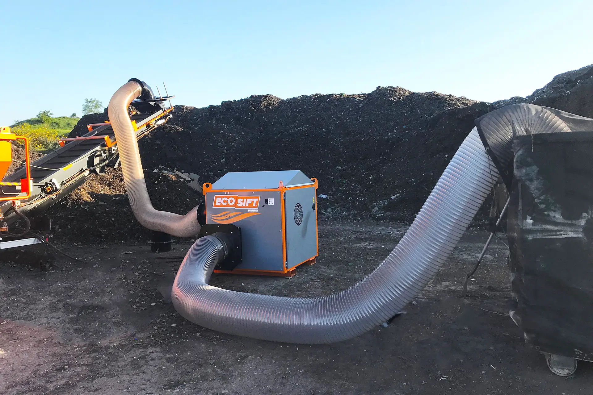 The EcoSift AERAS unit is shown connected to a machine's conveyor belt to separate materials.