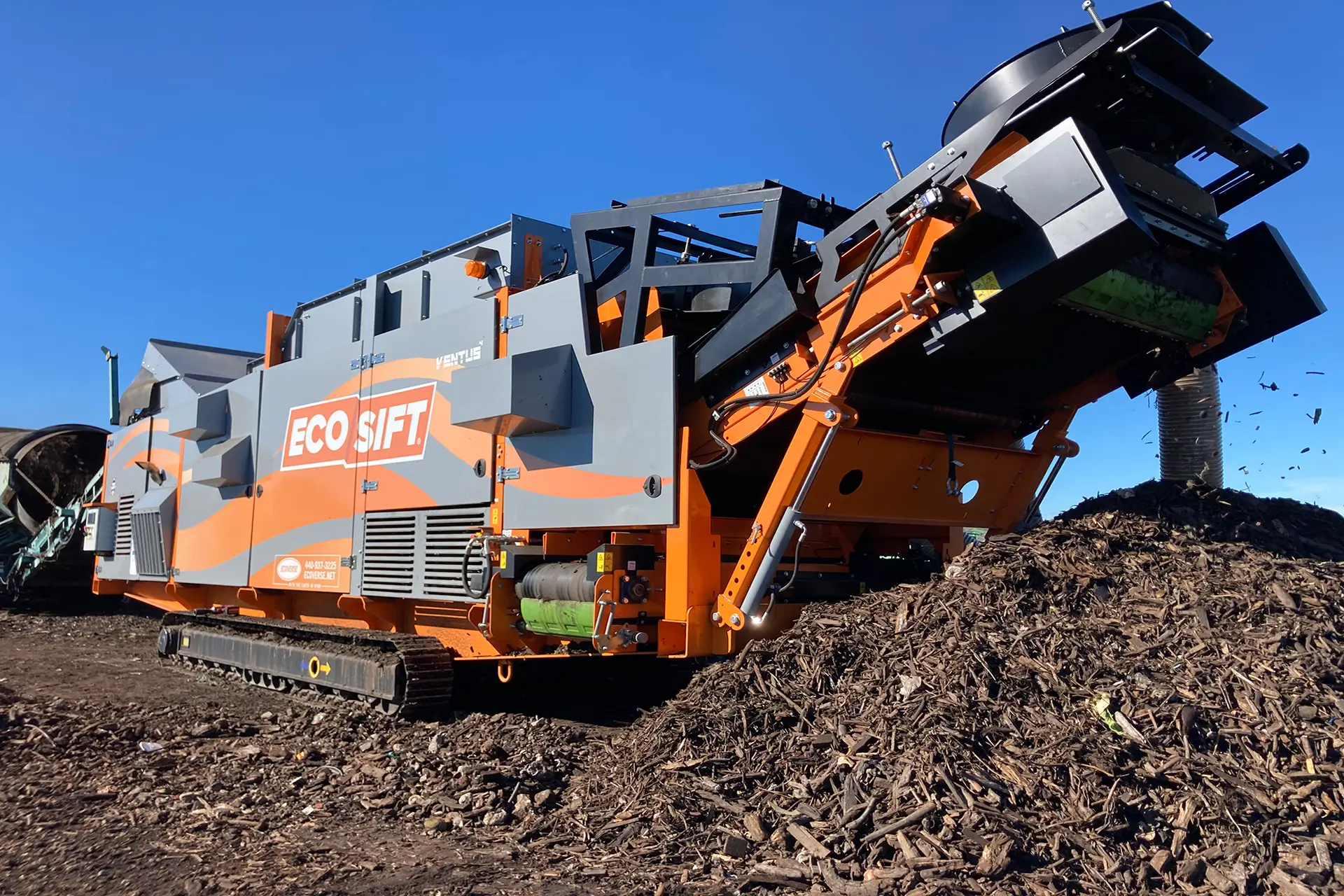 A tracked EcoSift Ventus machine sits among piles of mulch.