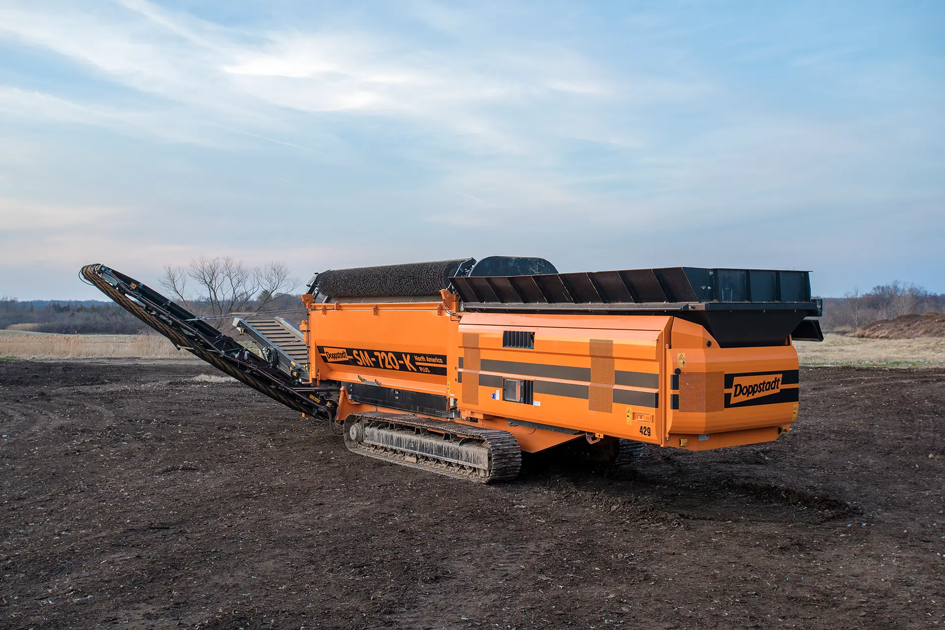 A Doppstadt SM 720 trommel screen sits in a compost facility with its conveyors extended.