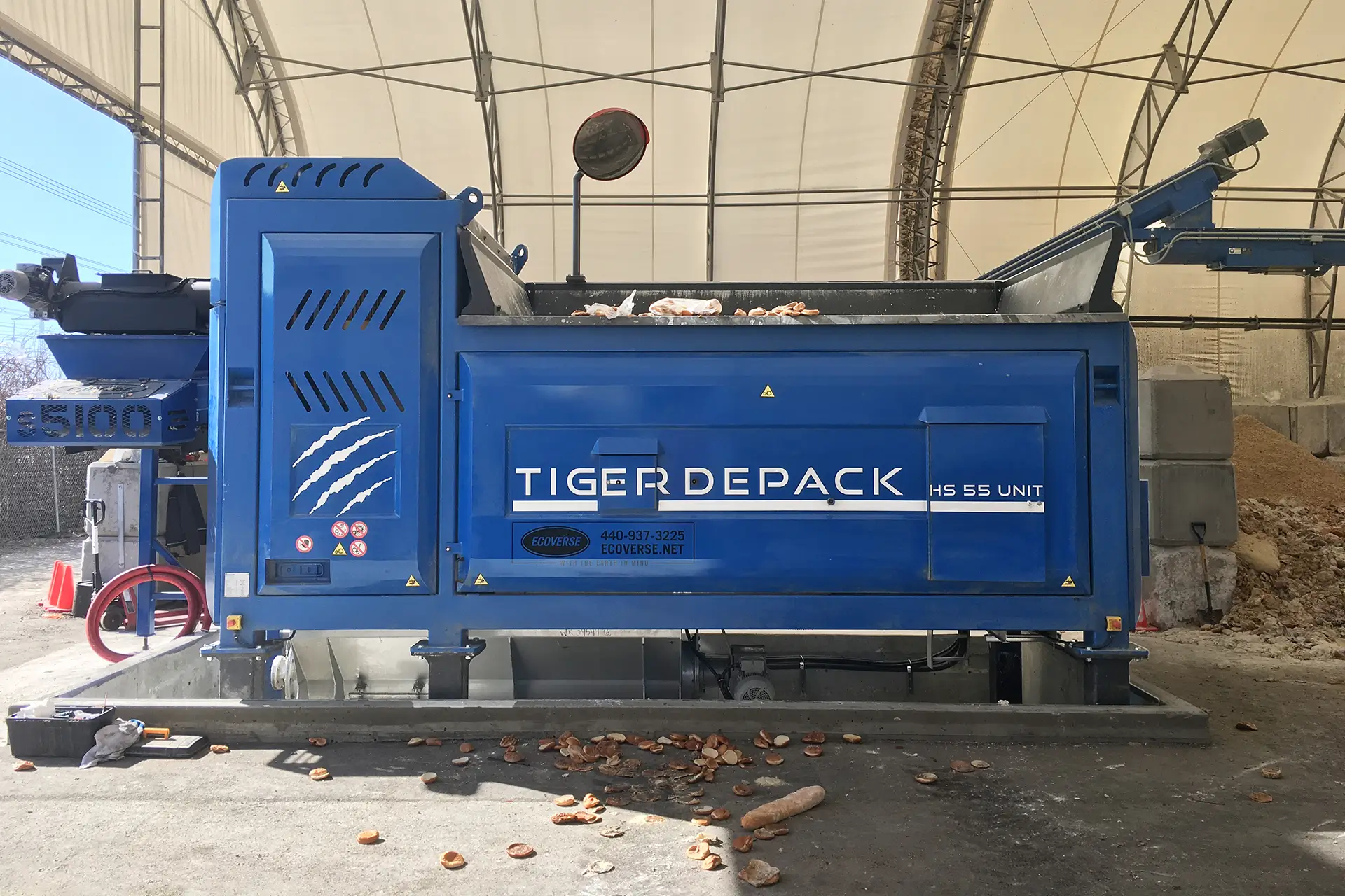 A blue Tiger Depack HS-55 waste food processing machine sits in a covered facility.