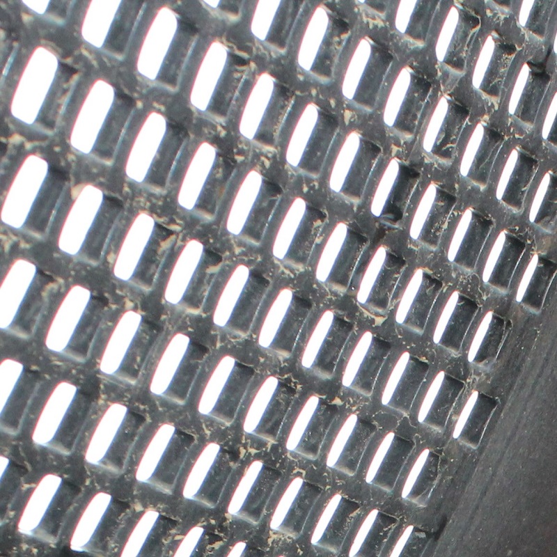 A close-up of a punch plate showing the thickness of the trommel's drum.