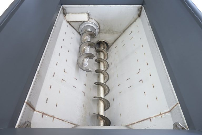 A horizontal auger in a Tiger depack machine is seen from above.