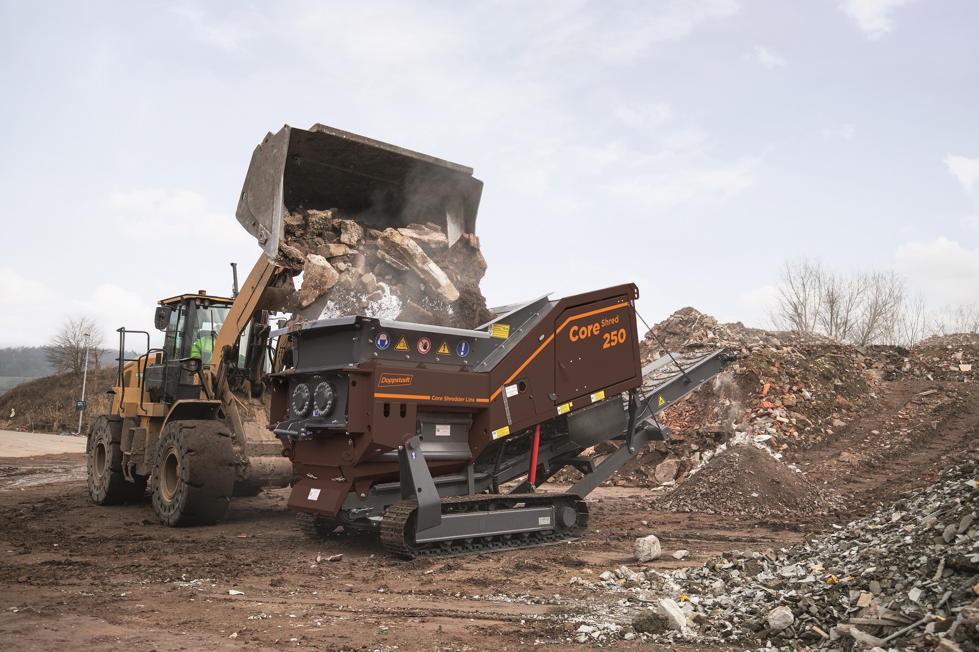 A CoreShred 250 twin-shaft shredder is being fed C&D waste, including large pieces of concrete.