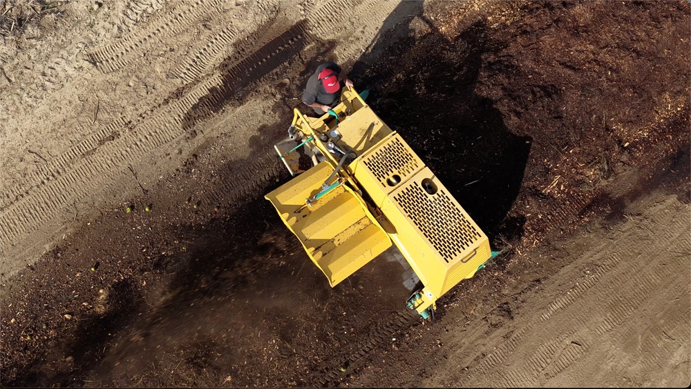 An overhead view of Catalyst BioAmendment's BACKHUS turner moving through a compost windrow.