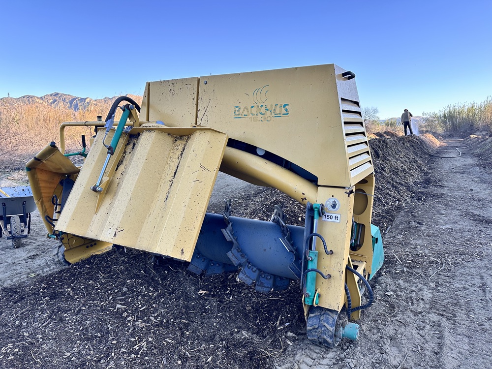 Catalyst BioAmendment's BACKHUS turner shown sitting astride a long windrow.
