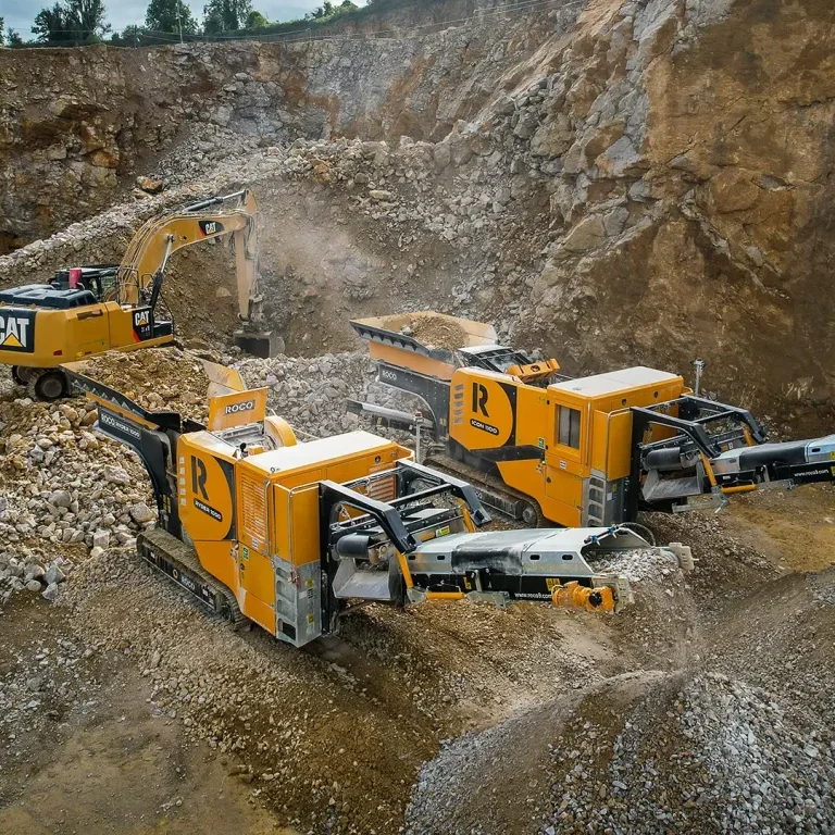 A jaw crusher and impact crusher sit side by side in a quarry, crushing rocks.