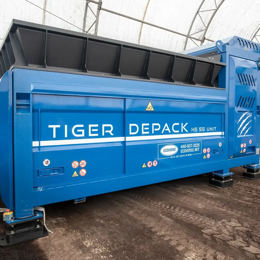A blue Tiger Depack HS-55 waste food processing machine sits in a covered facility with a dirt floor.